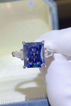 Radiant cut royal blue sapphire and moissanite ring with three stones.