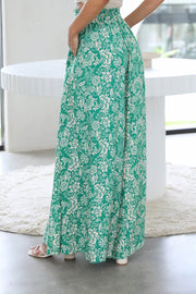 Botanical print palazzo trousers in green with a white floral pattern, featuring a wide leg and high waist.