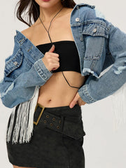 Distressed denim trucker jacket in medium wash with white fringe trim and frayed details.