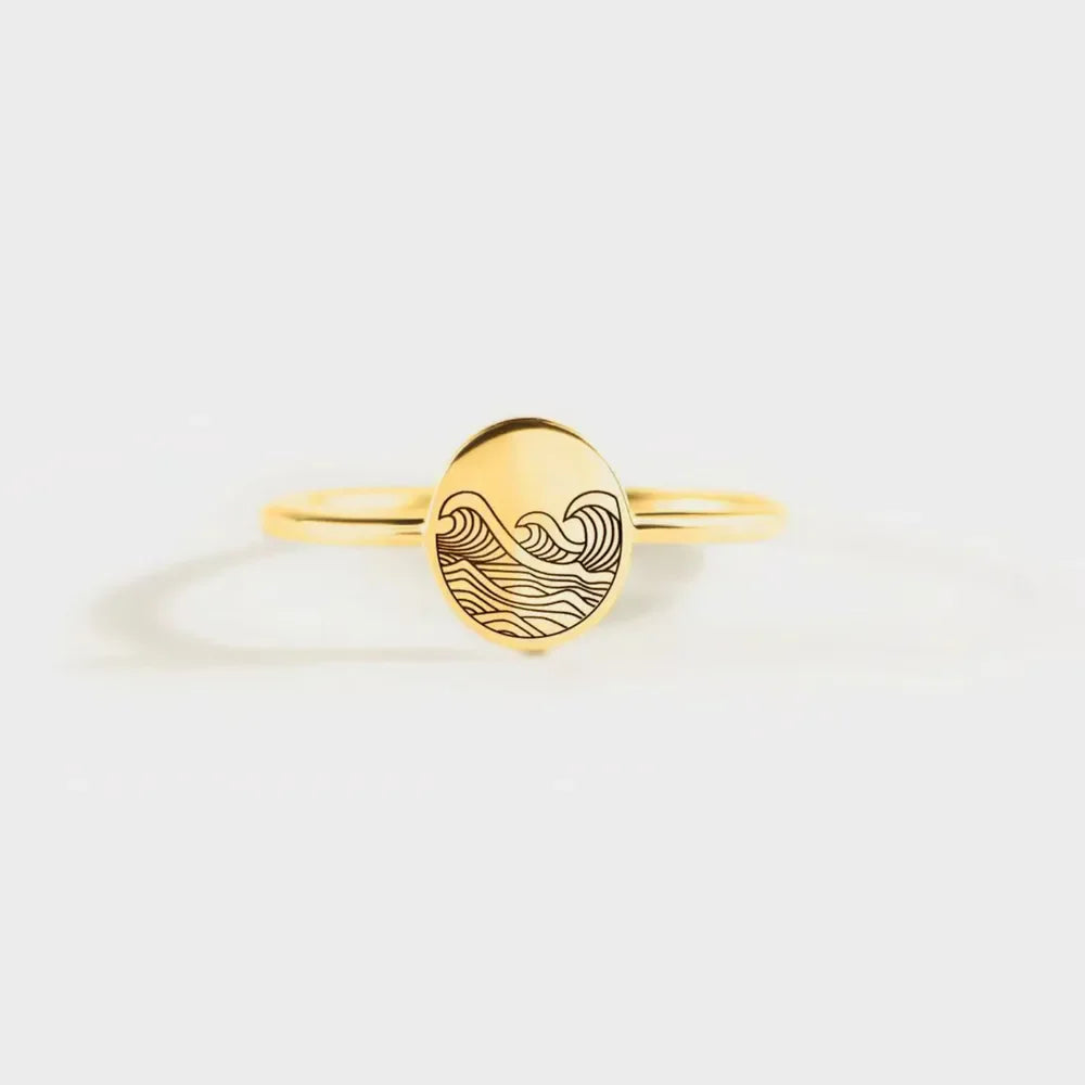 Gold band ring with engraved wave pattern on oval face