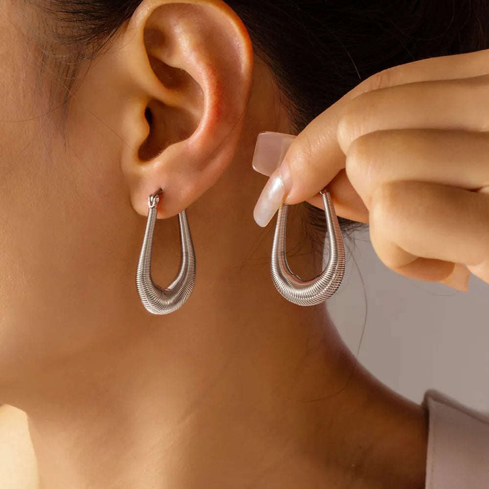 Silver coiled oval hoop earrings with a textured finish.