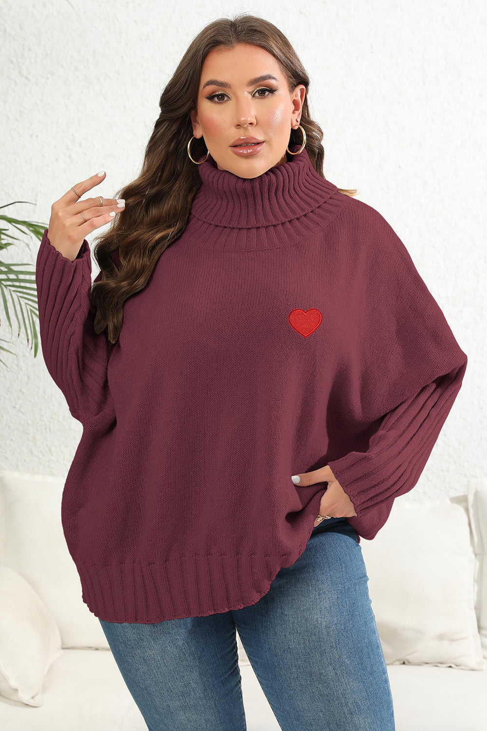 Wine turtleneck sweater with batwing sleeves and red heart appliqué detail.