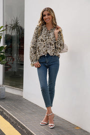 Animal print blouse with ruffle neckline and tie detail, long sleeves.