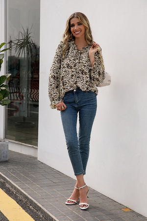 Animal print blouse with ruffle neckline and tie detail, long sleeves.
