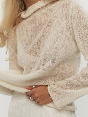 Sheer mock neck knit top in apricot with a draped fit and long sleeves.