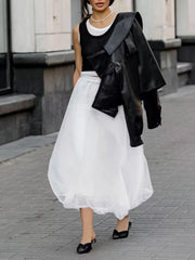 White midi skirt with sheer overlay and gathered hem, worn with black heels.