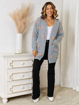 Gray knit cardigan with colorful starburst pattern, open front, long sleeves, and pockets.