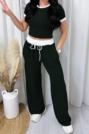 Ribbed black loungewear set with white contrast trim on crop top and wide leg pants.