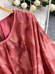 Elegant dress in rust with embroidered floral pattern and tie waist detail.