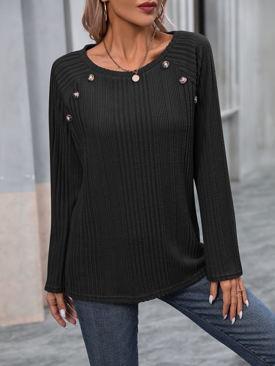 Black ribbed knit raglan sweater with button trim detail on the shoulder.