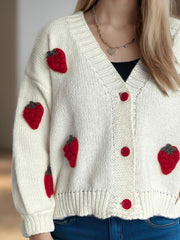 Cream knit cardigan with red strawberry appliqués and red buttons.