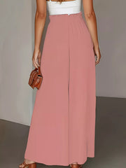 Pale blush wide-leg trousers with paperbag waist and a white top, held by a model.