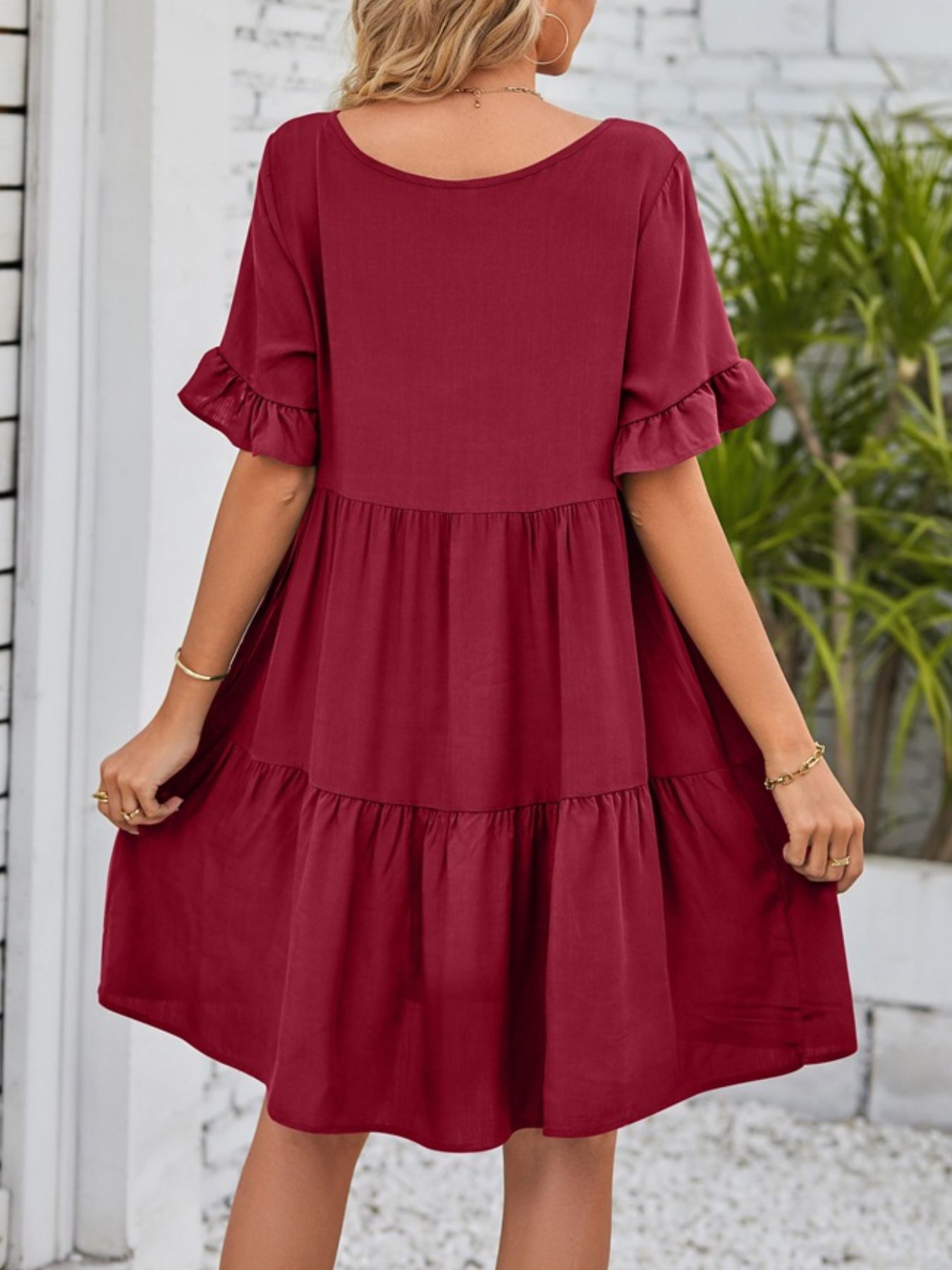 Burgundy tiered mini dress with ruffled short sleeves and a round neckline.