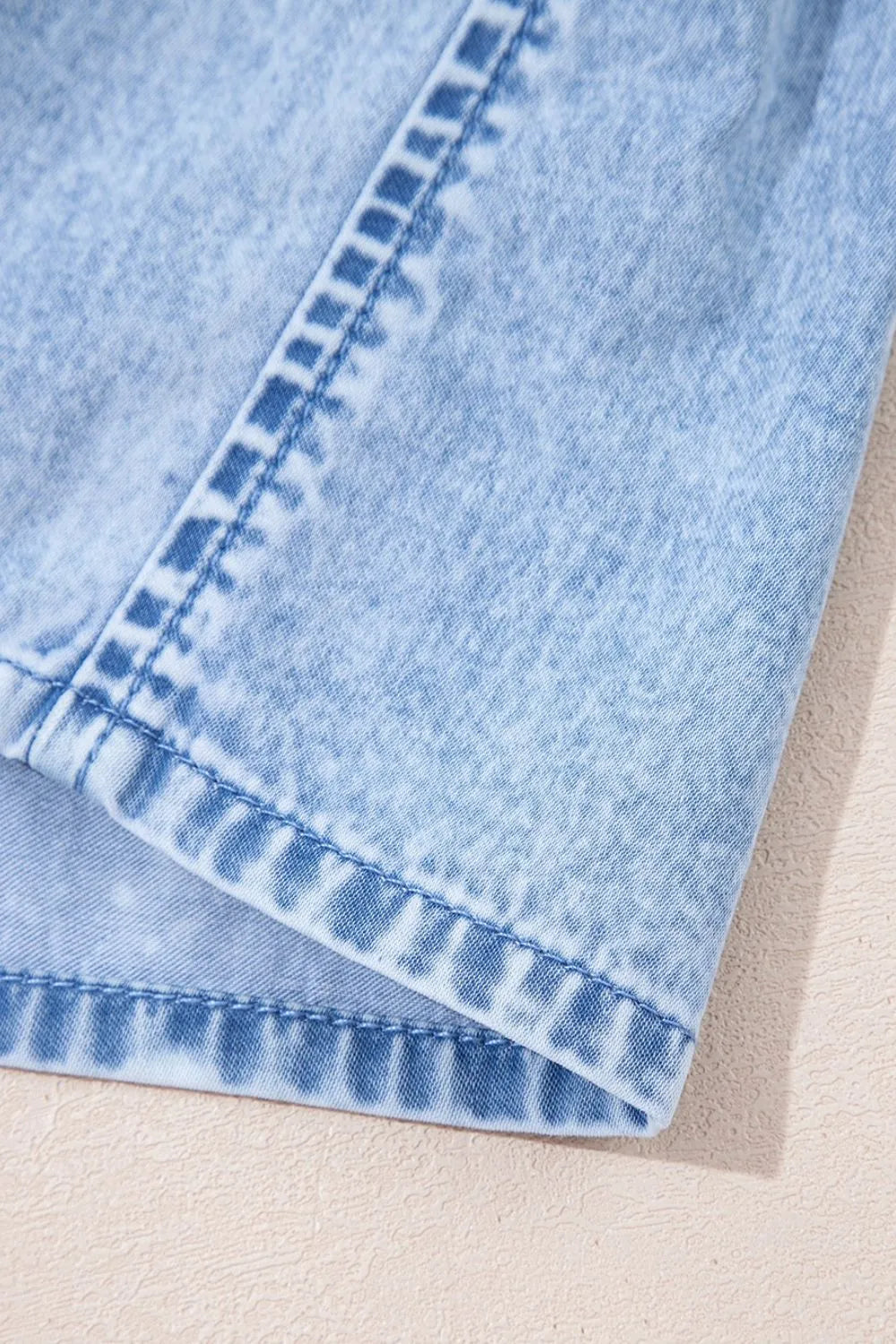 Light blue denim sundress with ruffled hem detail and visible stitching.