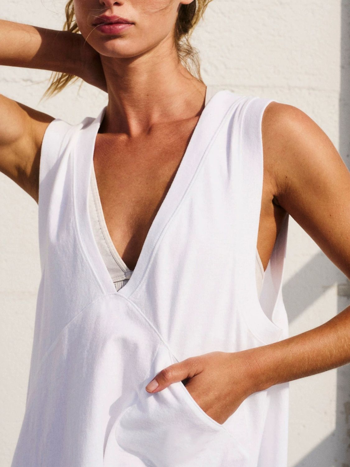 White wrap-front pocket tank top with deep V-neck and side pocket detail.