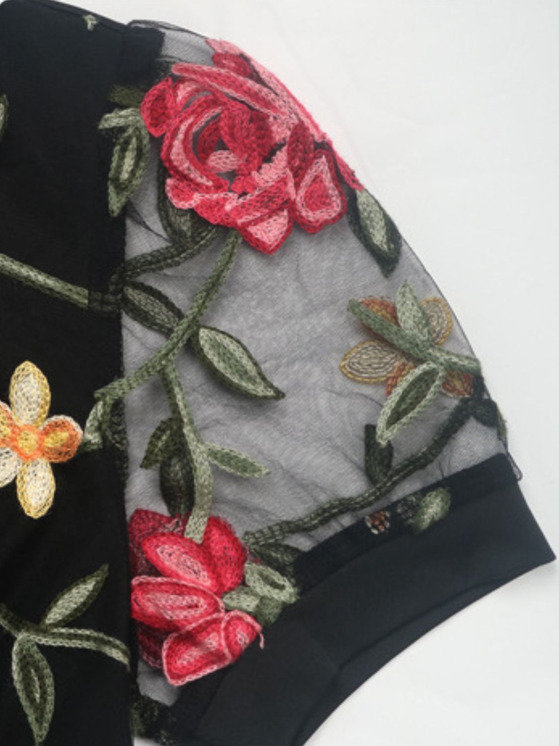 Black mesh sleeve bodysuit with embroidered floral details and a crew neck.
