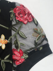Black mesh sleeve bodysuit with embroidered floral details and a crew neck.