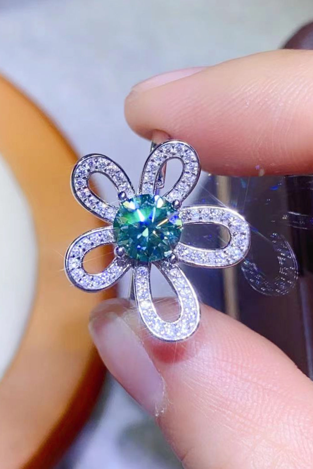 Petal halo ring with teal moissanite center and diamond accents.