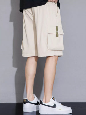 Khaki cargo shorts with a green tab detail on the pocket, worn by a man.