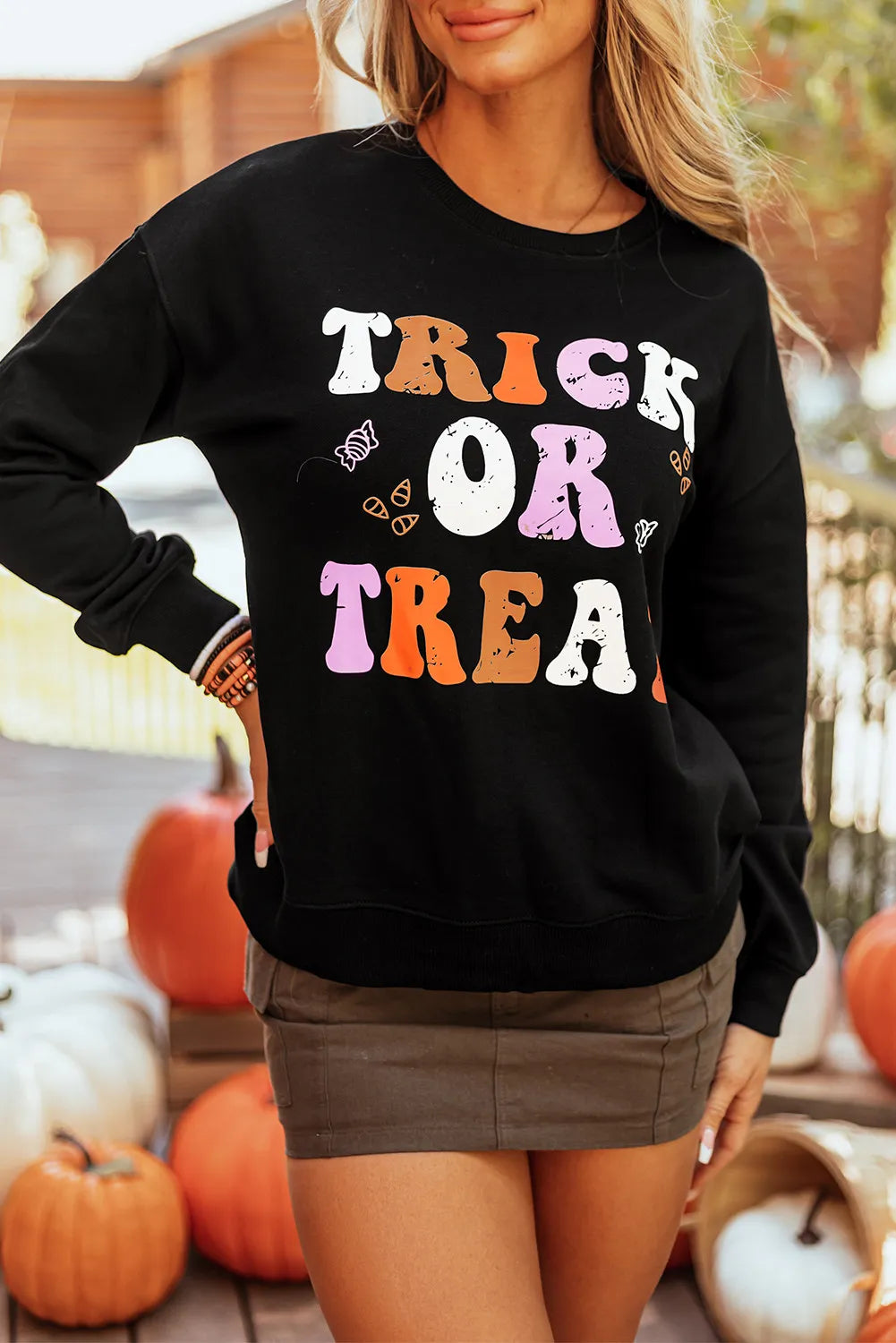 Black crewneck sweatshirt with "Trick or Treat" graphic and candy motifs.