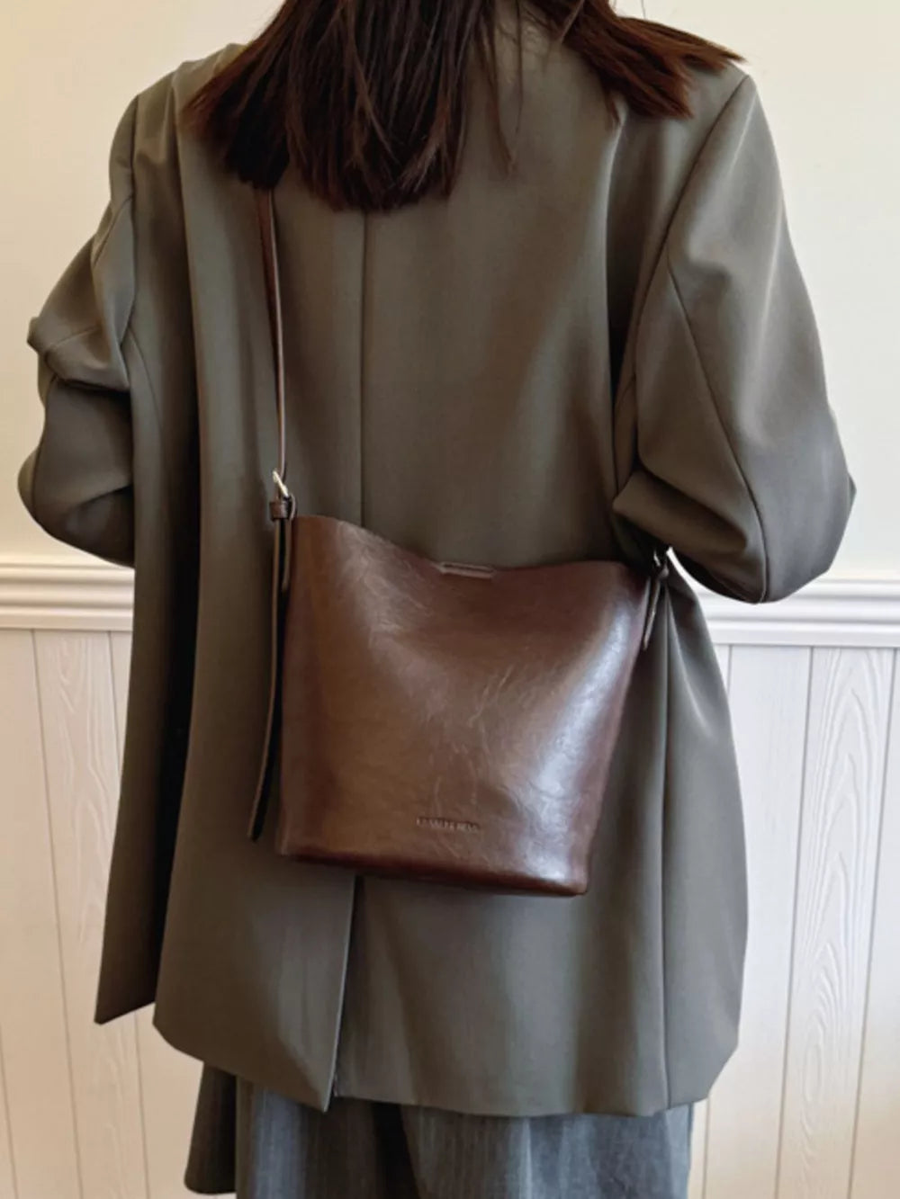 Distressed vintage bucket crossbody bag in brown leather with adjustable strap.