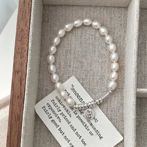 Delicate freshwater pearl bracelet with silver accents and a good luck charm.