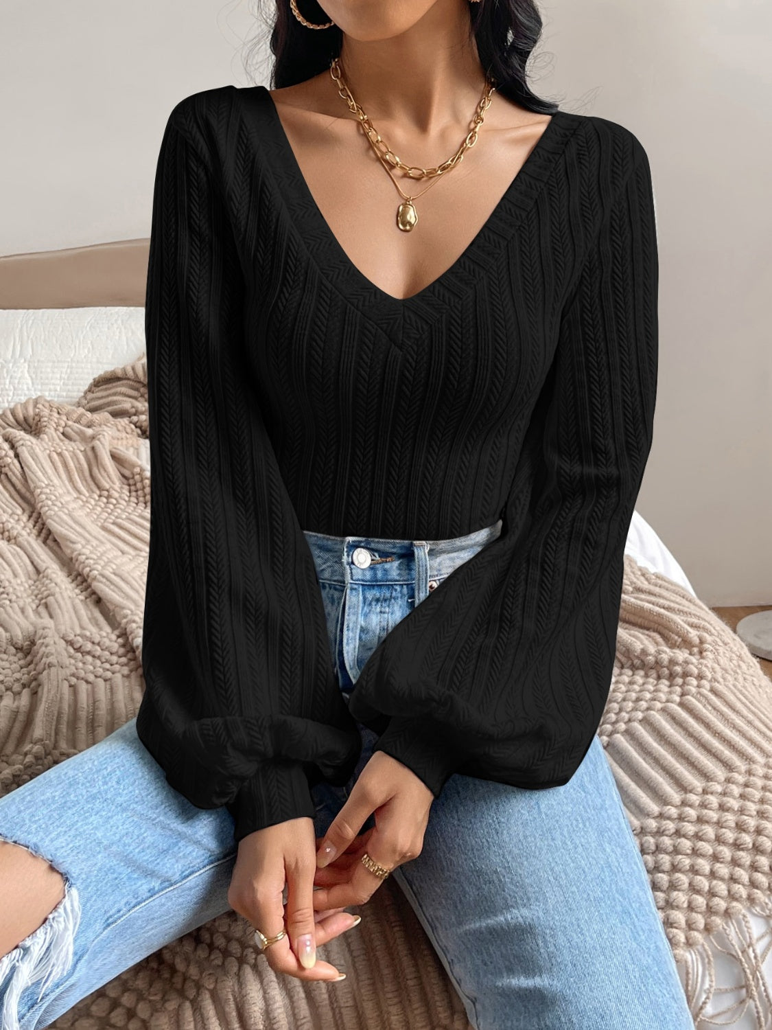 Black textured chevron blouson top with V-neck and voluminous sleeves