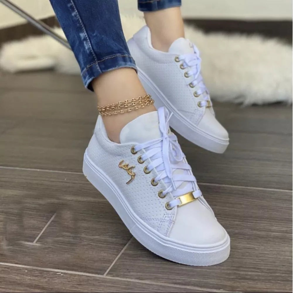 White perforated lace-up sneakers with gold accents and a gold lace tag.