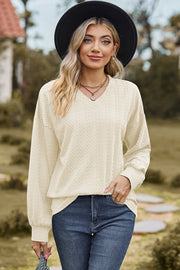 Beige cable knit V-neck pullover sweater with textured pattern and long sleeves.