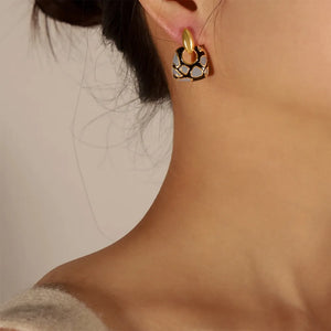 Geometric enamel drop earrings with gold accents and a black and grey pattern.