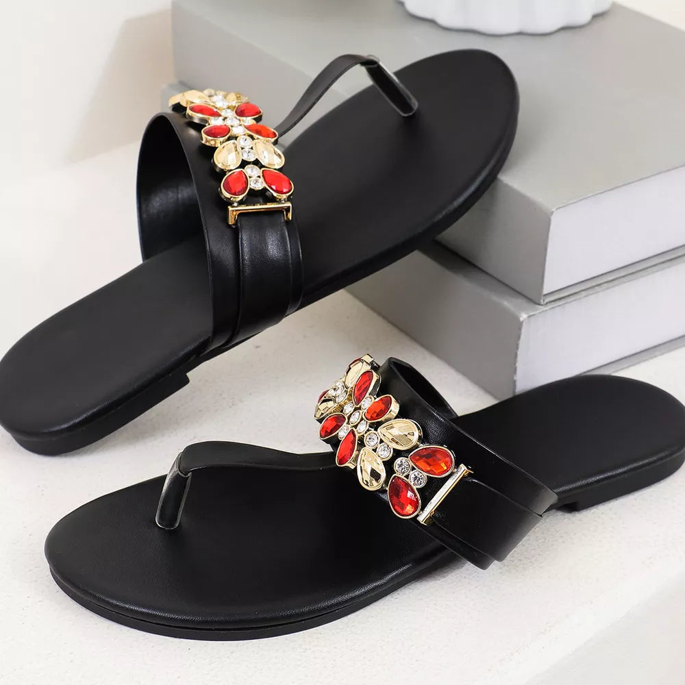 Black jeweled toe-post flat sandals with red and gold embellishments.