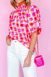 Brushstroke print blouse with ruffled neckline and puff sleeves, red and pink abstract pattern.