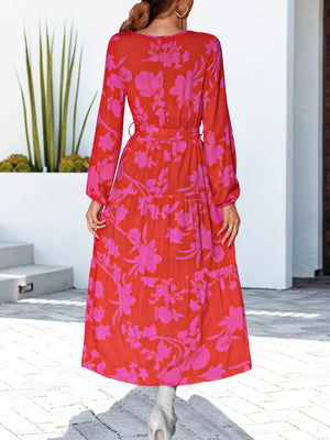 Tiered midi dress in hot pink floral print with tie waist and long sleeves.