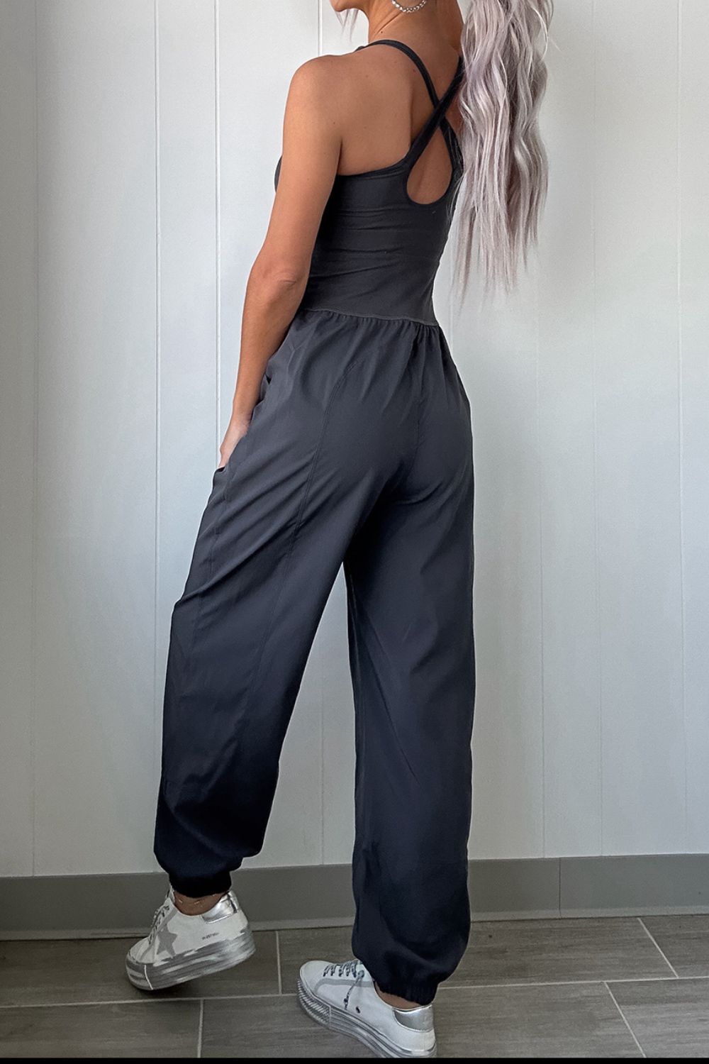 Dark gray cutout bodice gathered-leg jumpsuit with crisscross back detail and elastic cuffs.