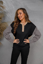 Colorblock henley knit sweater in black with tan and grey sleeves, featuring a button neckline.