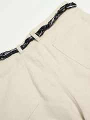 Cream white maternity pants with a black patterned braided belt and wide-leg cut.