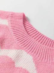 Pink acrylic knit sweater with white heart pattern and ribbed crew neck.