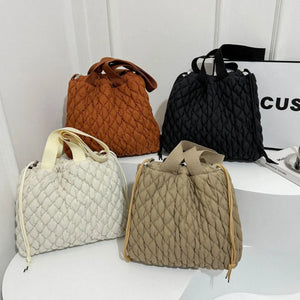 Quilted drawstring carryall bags in black, terracotta, ivory, and khaki.