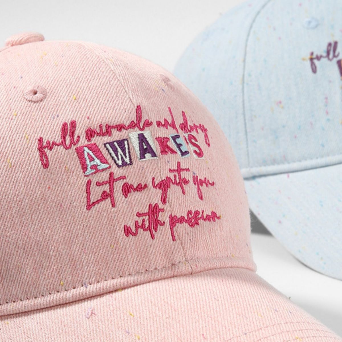 Pink embroidered text baseball cap with curved brim and speckle detail.