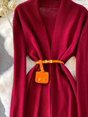 Burgundy knitted maxi dress and cardigan ensemble with orange belt and mini bag detail.