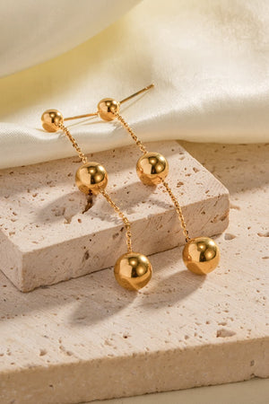 Gold triple orb drop earrings with delicate chain detail.