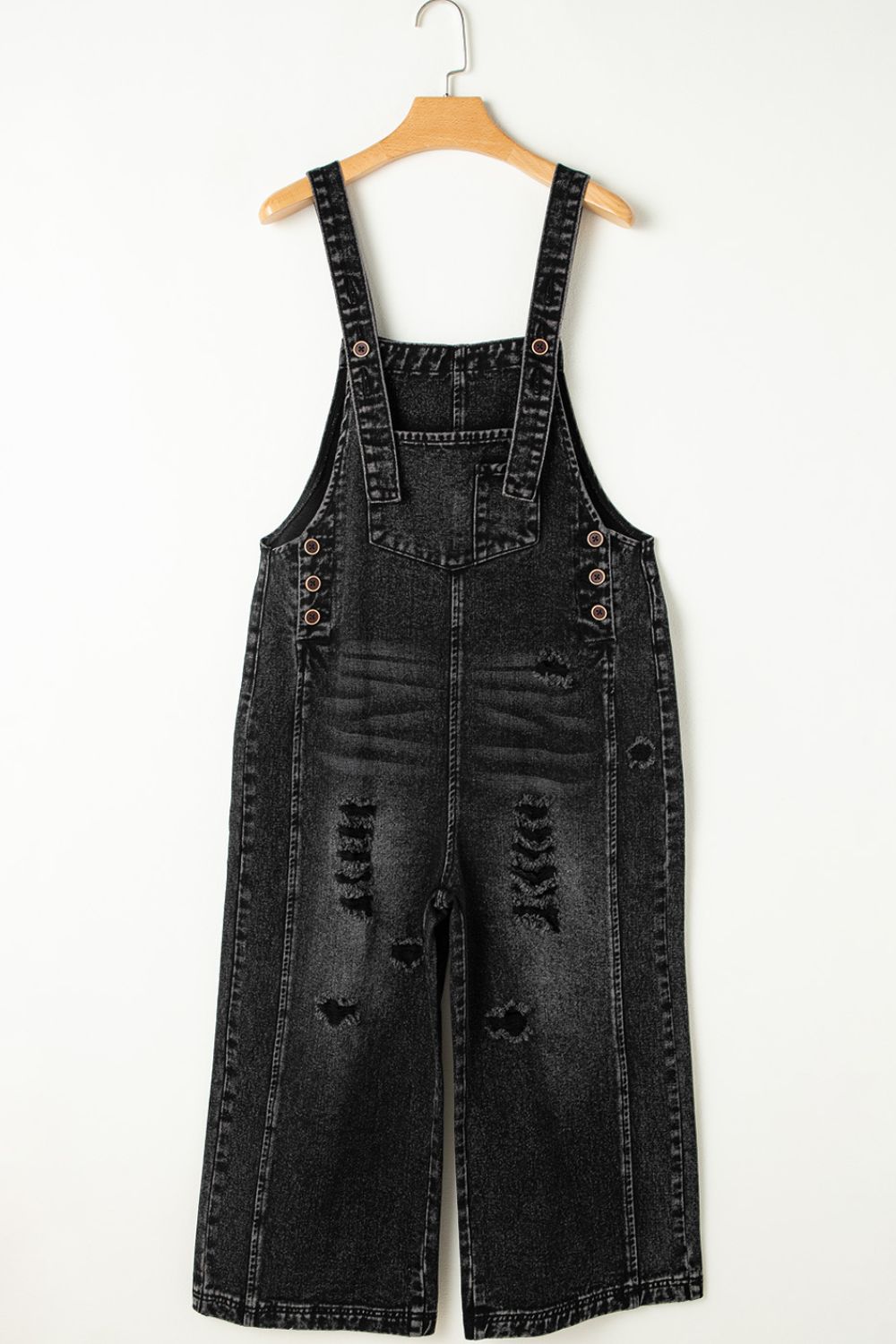 Black distressed denim culotte overalls with button closures and wide legs.