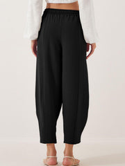 Black balloon trousers with elastic waist and sculpted seam detail.