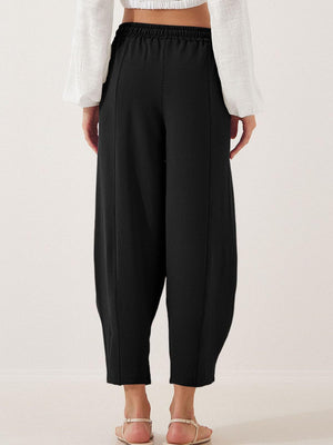 Black balloon trousers with elastic waist and sculpted seam detail.
