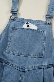 Denim jumpsuit with wide legs, front pocket holding a phone, and adjustable straps.