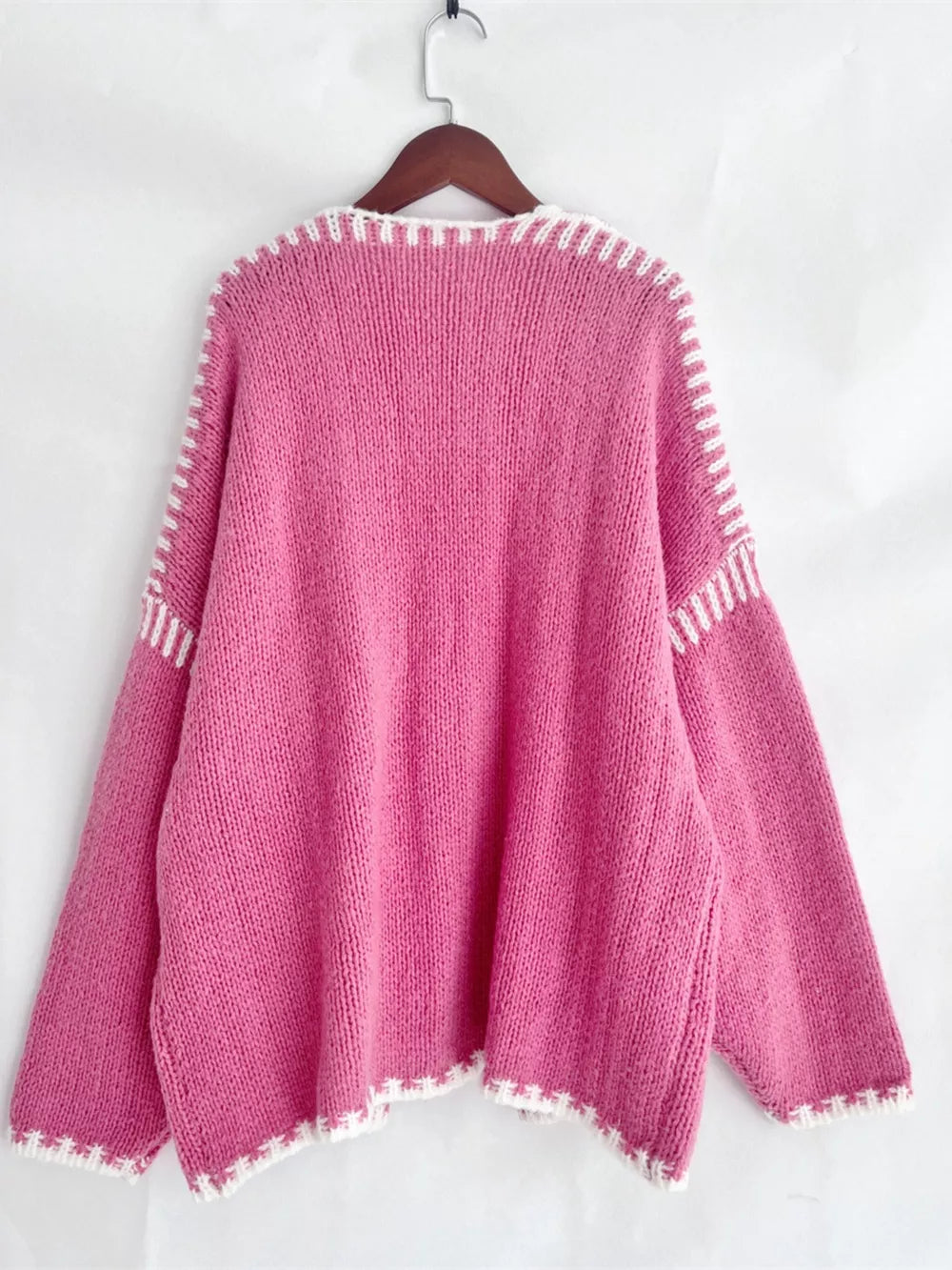 Oversized pink knit cardigan with white contrast trim and stitching detail.