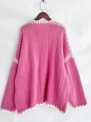 Oversized pink knit cardigan with white contrast trim and stitching detail.
