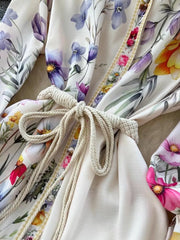 Vibrant floral midi dress with lantern sleeves, rope tie, and brocade trim.