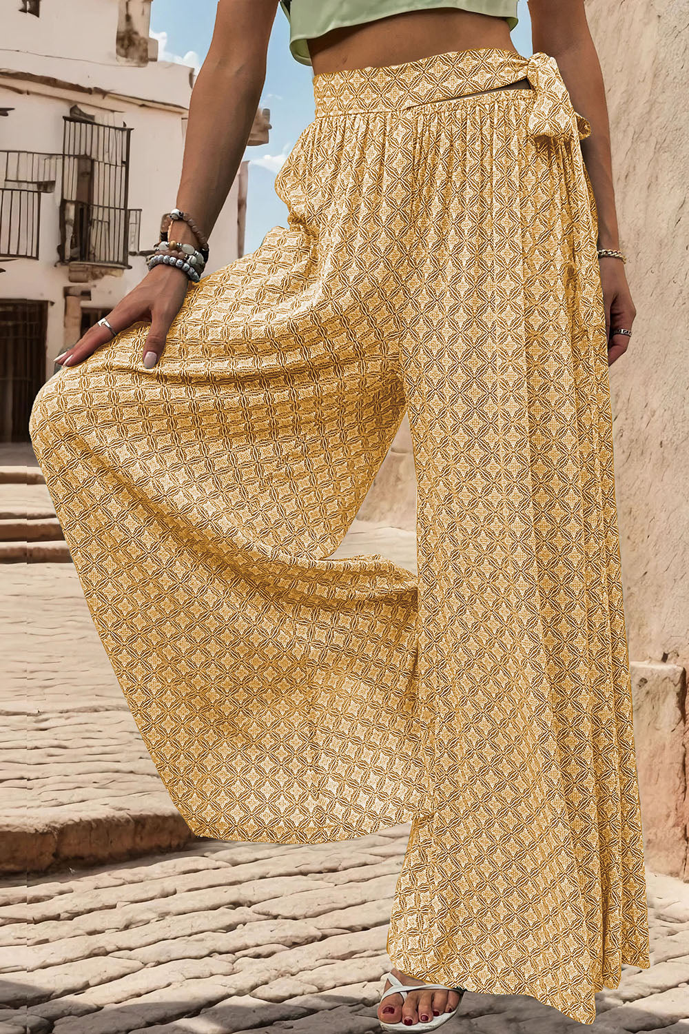 Yellow geometric print wide-leg palazzo trousers with a tie waist detail.