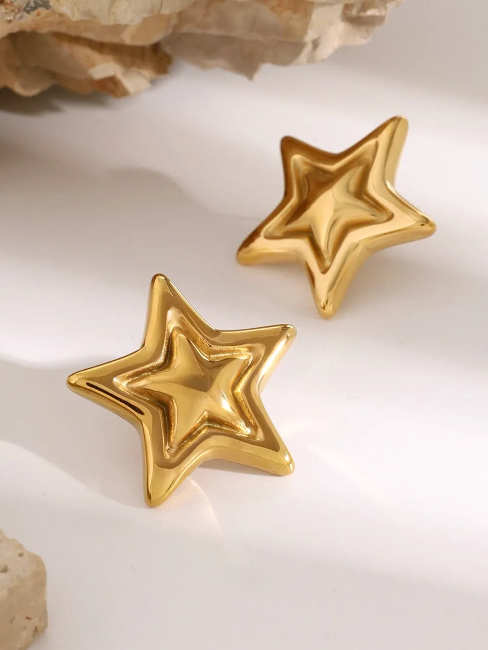 Gold starburst stud earrings with sculpted, layered design.
